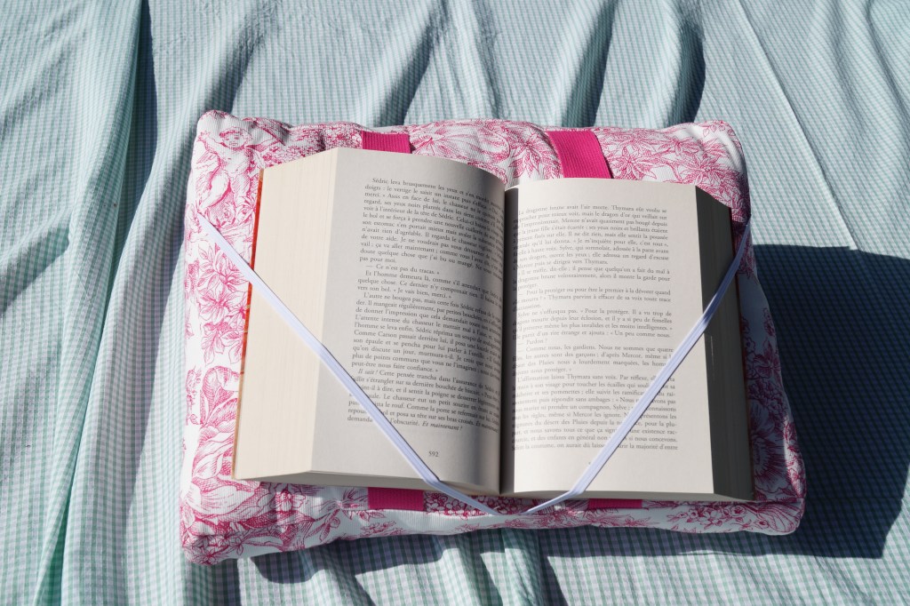 Coussin de lecture en toile de jouy rose - les pages du livre sont ouvertes et maintenues en place grâce à des élastiques
